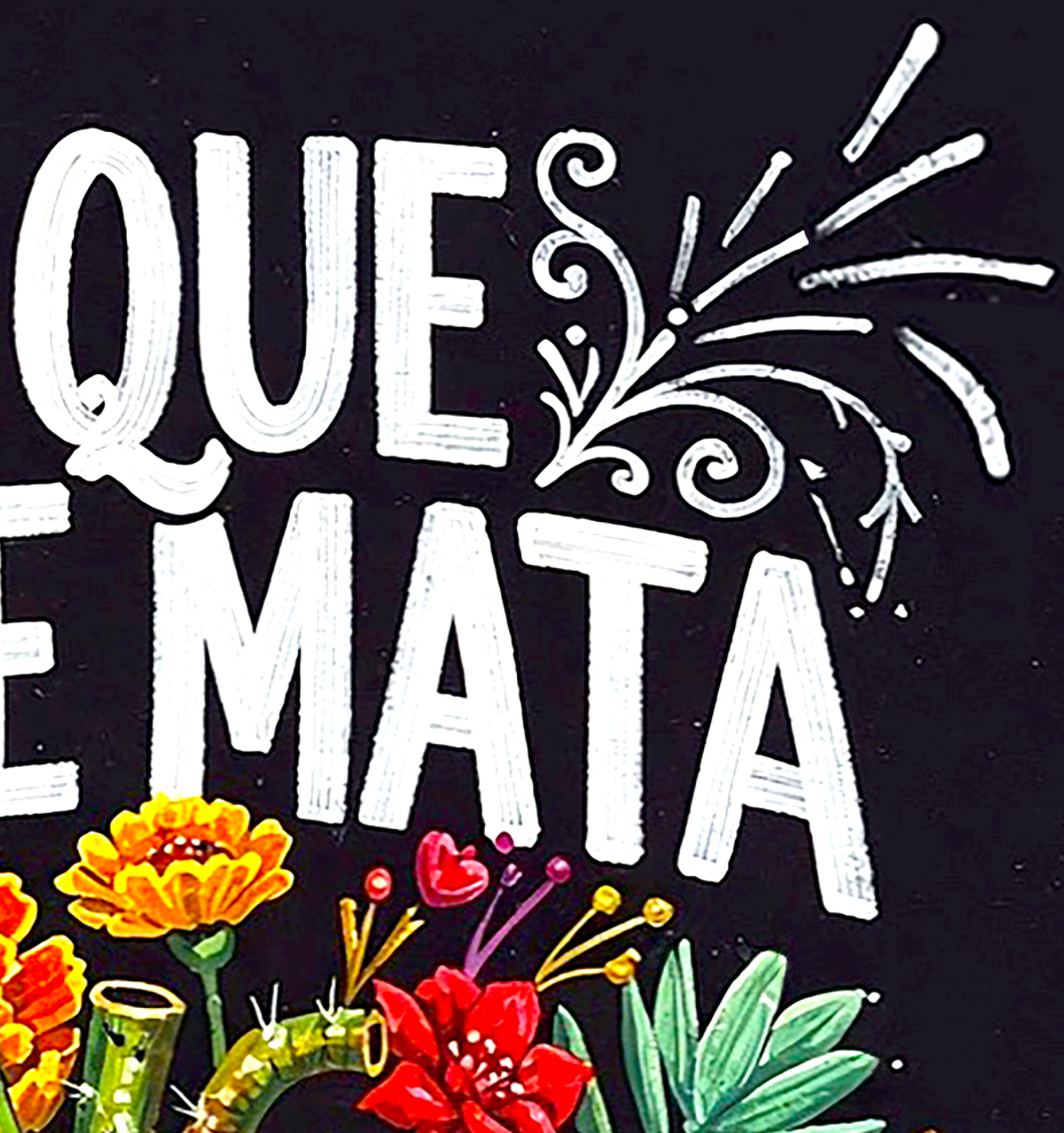 A close-up of a graphic design featuring the Spanish phrase 'QUE E MATA' in large white hand-painted style letters on a black background, decorated with white flourishes and surrounded by colorful flowers and green leaves at the bottom.