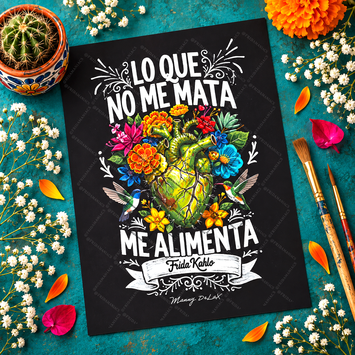 A black art print featuring a colorful anatomical heart illustration with flowers, hummingbirds, and white Spanish text reading 'LO QUE NO ME MATA ME ALIMENTA' with 'Frida Kahlo' and 'Mangy DUK' below. The print is styled in a flat-lay on a teal surface surrounded by a cactus in a pot, orange flowers, baby's breath, petals, and paintbrushes.