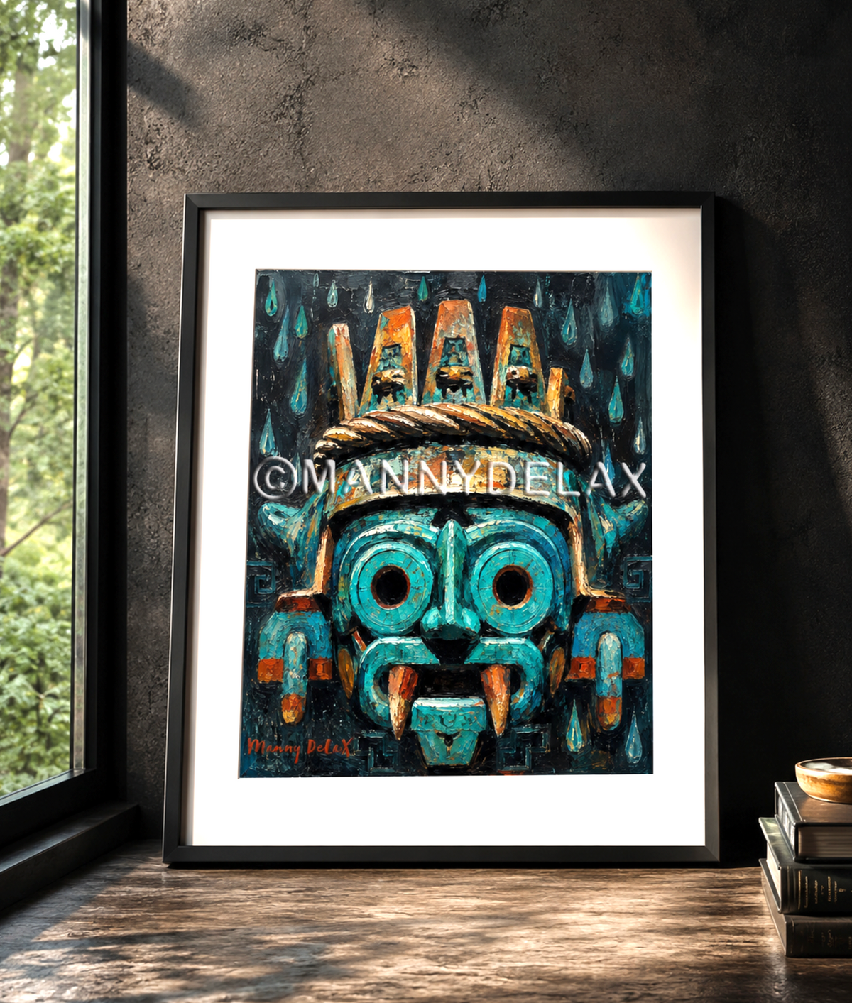 A framed art print featuring a stylized turquoise and black mask with orange accents, leaning against a dark wall on a wooden floor next to a window.