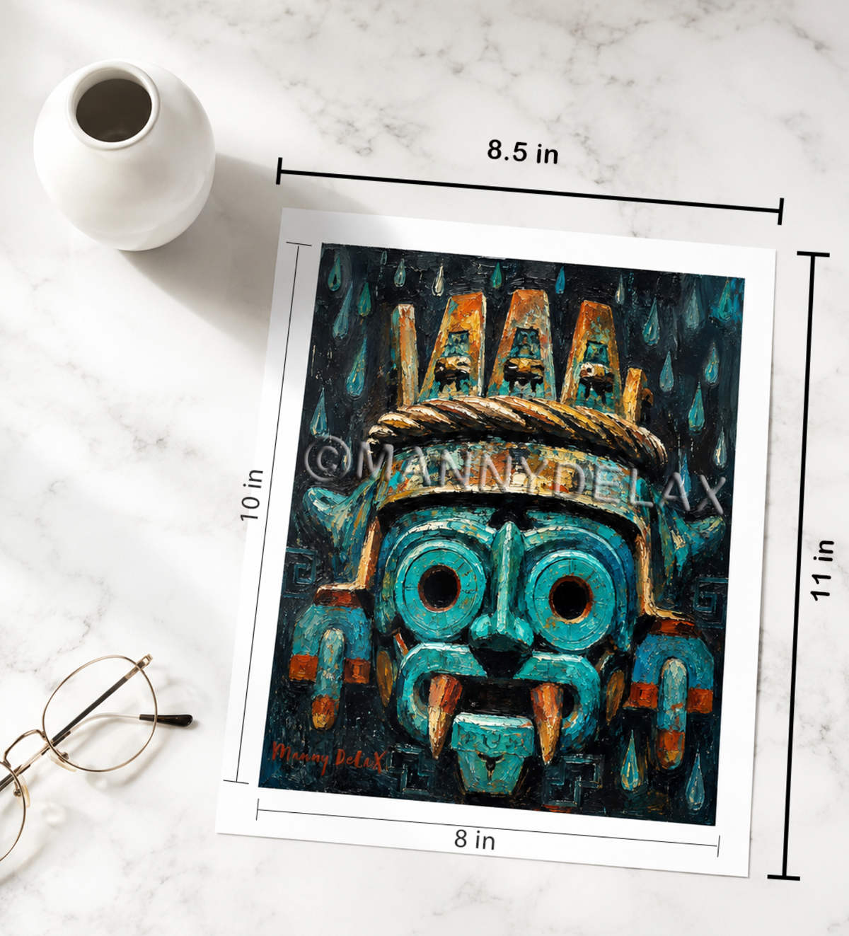 A square art print featuring a stylized turquoise and black mask with orange accents, shown on a white marble surface with dimension lines indicating 8.5 in by 11 in.