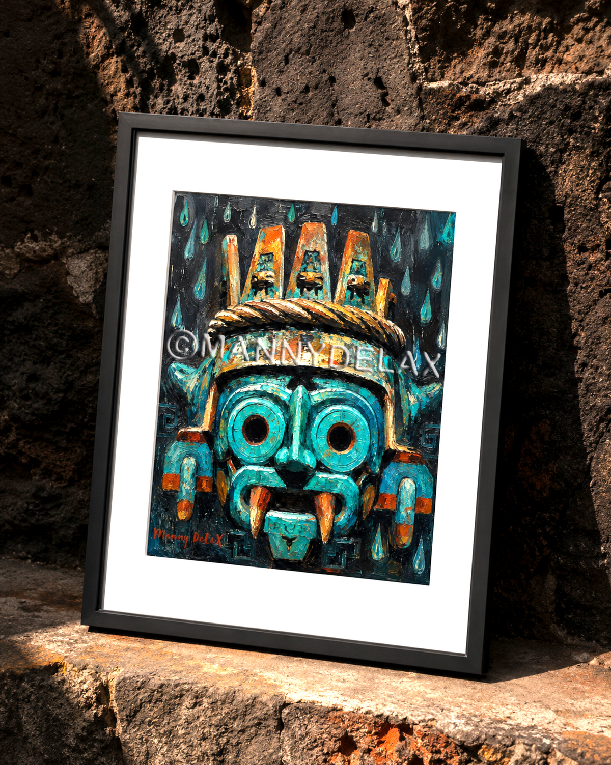 A framed art print featuring a stylized turquoise and orange Aztec-style mask, leaning against a rustic dark stone wall. Tlaloc art by Manny DeLaX