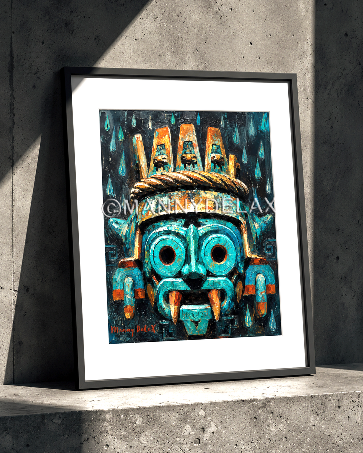 A framed art print featuring a stylized Aztec-inspired mask in vibrant turquoise, teal, and orange, displayed on a concrete ledge against a textured gray wall.