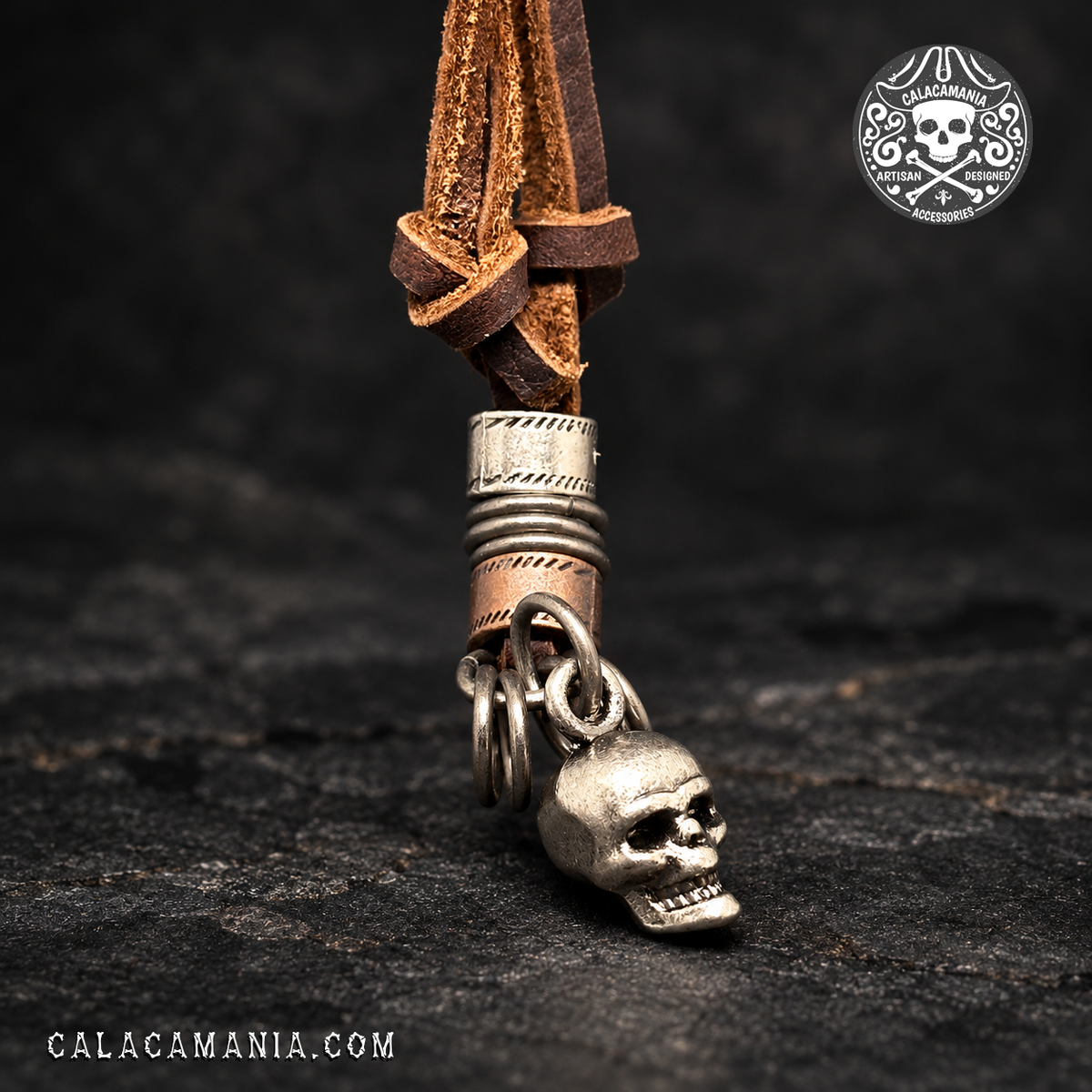 Rustic silver metal skull pendant detail with metallic rings and decorative circles pending from brown leather cords
